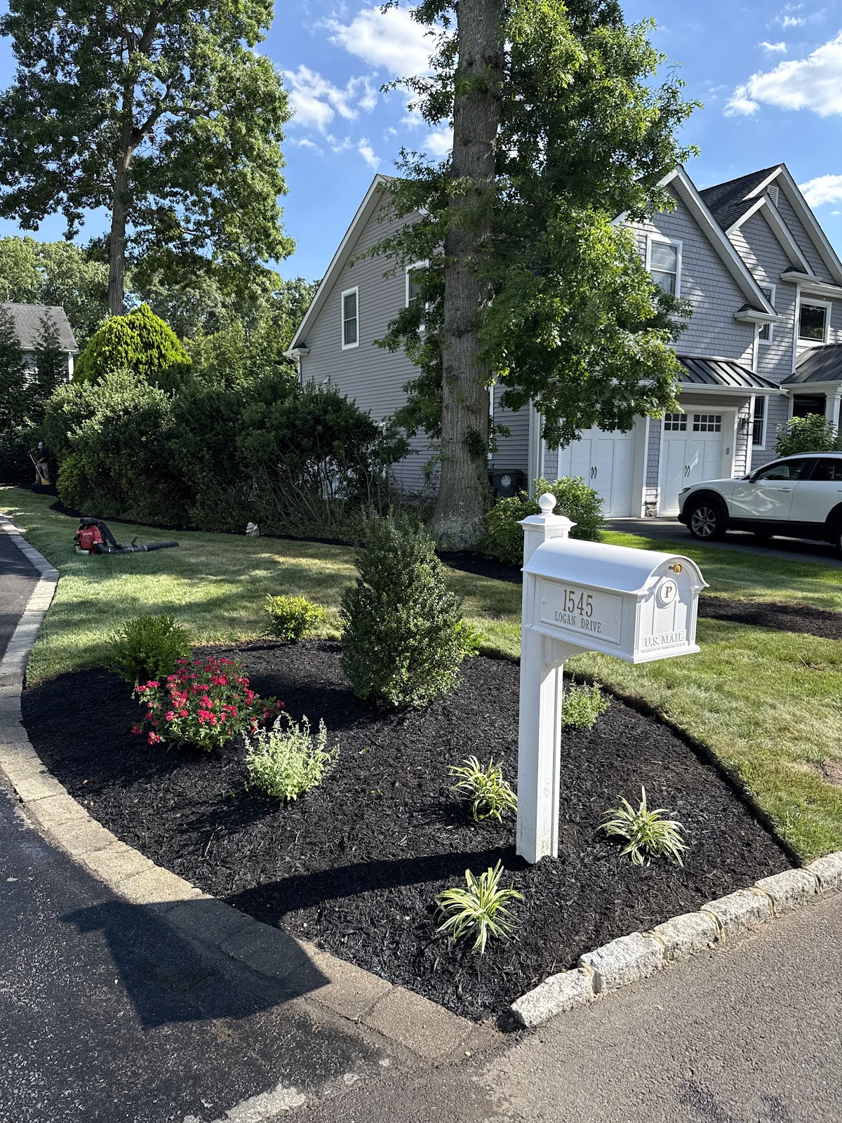 Finished mailbox garden bed with fresh mulch and flowers
