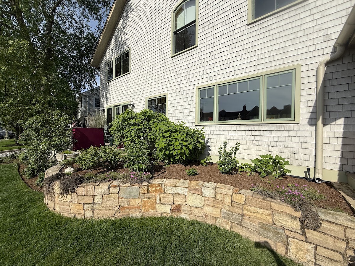 Raised stone retaining wall garden bed along a house foundation